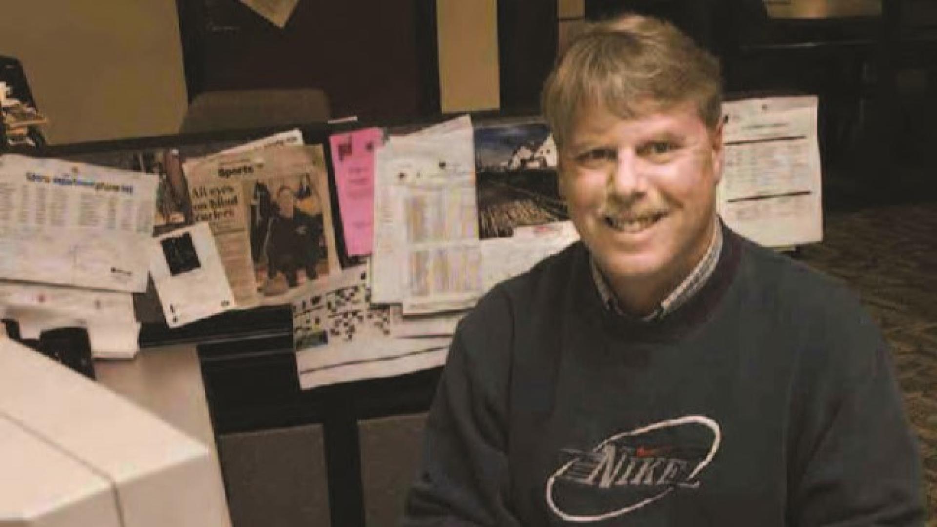 Dan Stinton smiles from behind a large old-fashioned white computer.